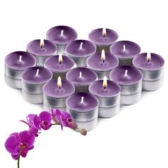 a bunch of purple candles sitting on top of each other next to a pink flower