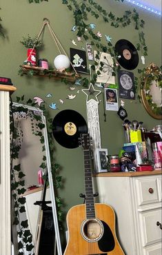 an acoustic guitar sitting on top of a wooden floor next to a wall covered in pictures