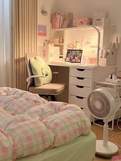 a bedroom with a bed, desk and fan in the corner next to a window