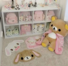 stuffed animals and other toys are on the floor in front of a white shelf filled with pink items