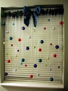 the window is decorated with balls hanging on a rod and ribbon tied at the top