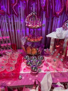 a pink table topped with lots of desserts and balloons