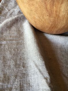 a wooden bowl sitting on top of a table next to a cloth covered chair cushion