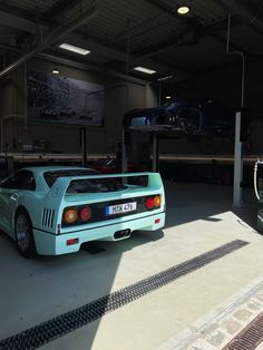 a blue sports car parked in a garage next to a green vehicle on the ground