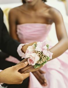 a person in a pink dress holding a flower on their arm with another woman's hand