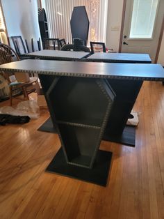 two black tables sitting on top of a hard wood floor next to a chair and desk