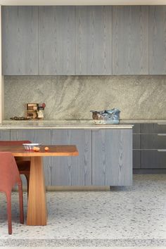 a modern kitchen with wood cabinets and marble counter tops, along with a dining room table