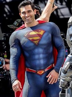 a man dressed as superman waves at the camera while standing in front of a crowd