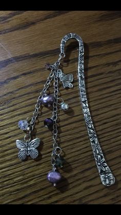 a close up of a necklace on a wooden table with beads and charms hanging from it