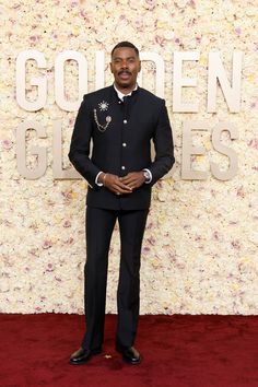 a man in a suit and tie standing on a red carpet with the words golden globes