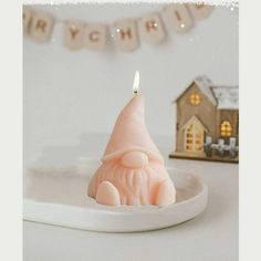 a candle that is sitting on a plate in the middle of a table with a small house