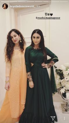 two women standing next to each other wearing long dresses and holding hands on their hips