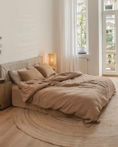 a large bed sitting in a bedroom on top of a wooden floor next to a window