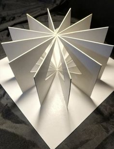 an origami sculpture is shown on a black surface with the light shining through it