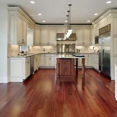 a large kitchen with wooden floors and white cabinets