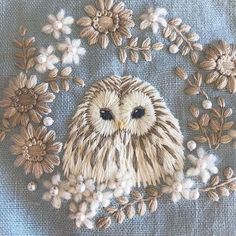 an embroidered owl with flowers on it's head is shown in the middle of a piece of cloth