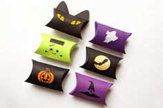 four different colored paper bags with black cats, pumpkins and ghost faces on them