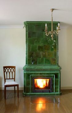 a green fireplace with a chandelier hanging over it