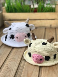 two crocheted cow hats sitting on top of a wooden table