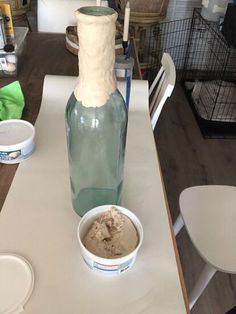 there is a bottle and bowl on the table with ice cream in front of it