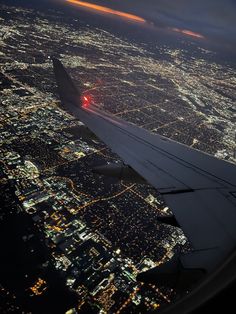 an airplane wing flying over the city lights at night