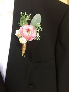 a boutonniere with pink flowers and greenery is worn on a man's black suit