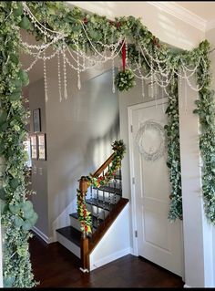 an entry way decorated for christmas with greenery and garland on the railing, along with wreaths