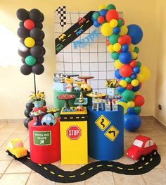 a birthday party with balloons, cars and traffic signs on the floor in front of a balloon arch