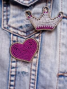 a pink heart with a crown on it is in the pocket of someone's jean jacket