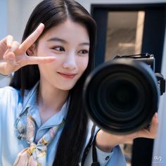 a woman is holding up her camera and making the peace sign