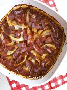 a casserole dish with onions and bacon in it on a red and white checkered tablecloth