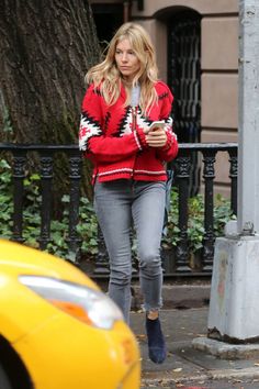 a woman walking down the street while looking at her cell phone