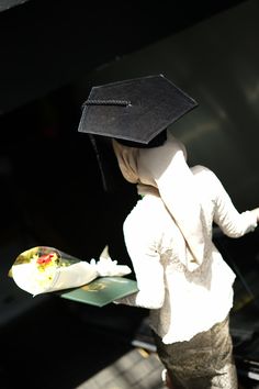 a woman wearing a graduation cap and holding a hot dog in one hand and a sandwich in the other