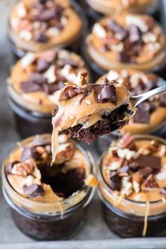 a spoon is lifting up some desserts out of the cupcake tin to be eaten