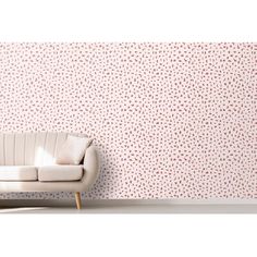 a white couch sitting in front of a wall covered in pink and brown dots on it