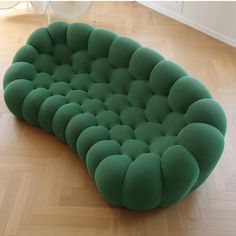 a green couch sitting on top of a hard wood floor