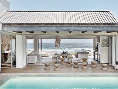 an outdoor living area with a pool and dining table next to the ocean in front of it