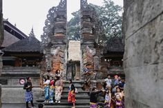 many people are standing in front of an old building with stone pillars and ornate carvings