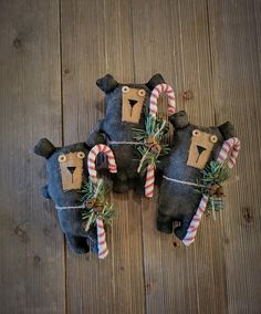 three stuffed animals with candy canes tied to them on a wooden floor next to christmas decorations