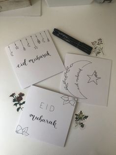 three cards with writing on them sitting next to a pen and some other items that include flowers