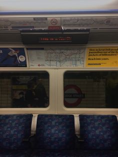 an empty train car with blue seats and signs on the wall above it's windows