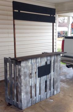 an outdoor bar made out of old pallets and wooden planks with a truck parked in the background