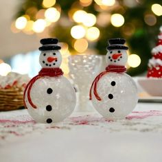 two glass snowmen sitting on top of a table