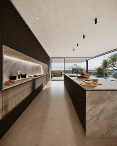 a kitchen with marble counter tops and shelves next to a large window that overlooks the water