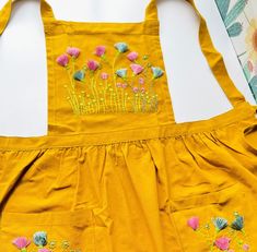 a yellow apron with flowers embroidered on it