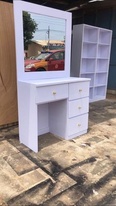 a white desk with a mirror on it and some drawers in front of the door