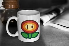 a coffee mug with a flower on it sitting next to a book and a pen