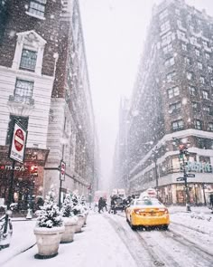 a yellow taxi cab driving down a snow covered street