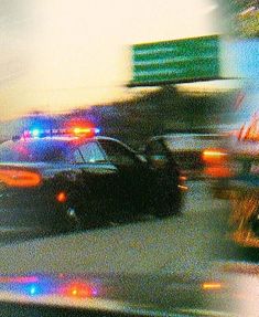 two police cars driving down the street at night