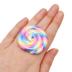 a hand holding a colorful lollipop in it's palm